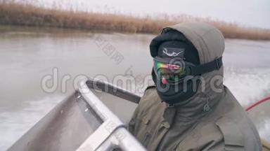一个穿着保暖衣服和滑雪护目镜的渔夫很快就骑上船
